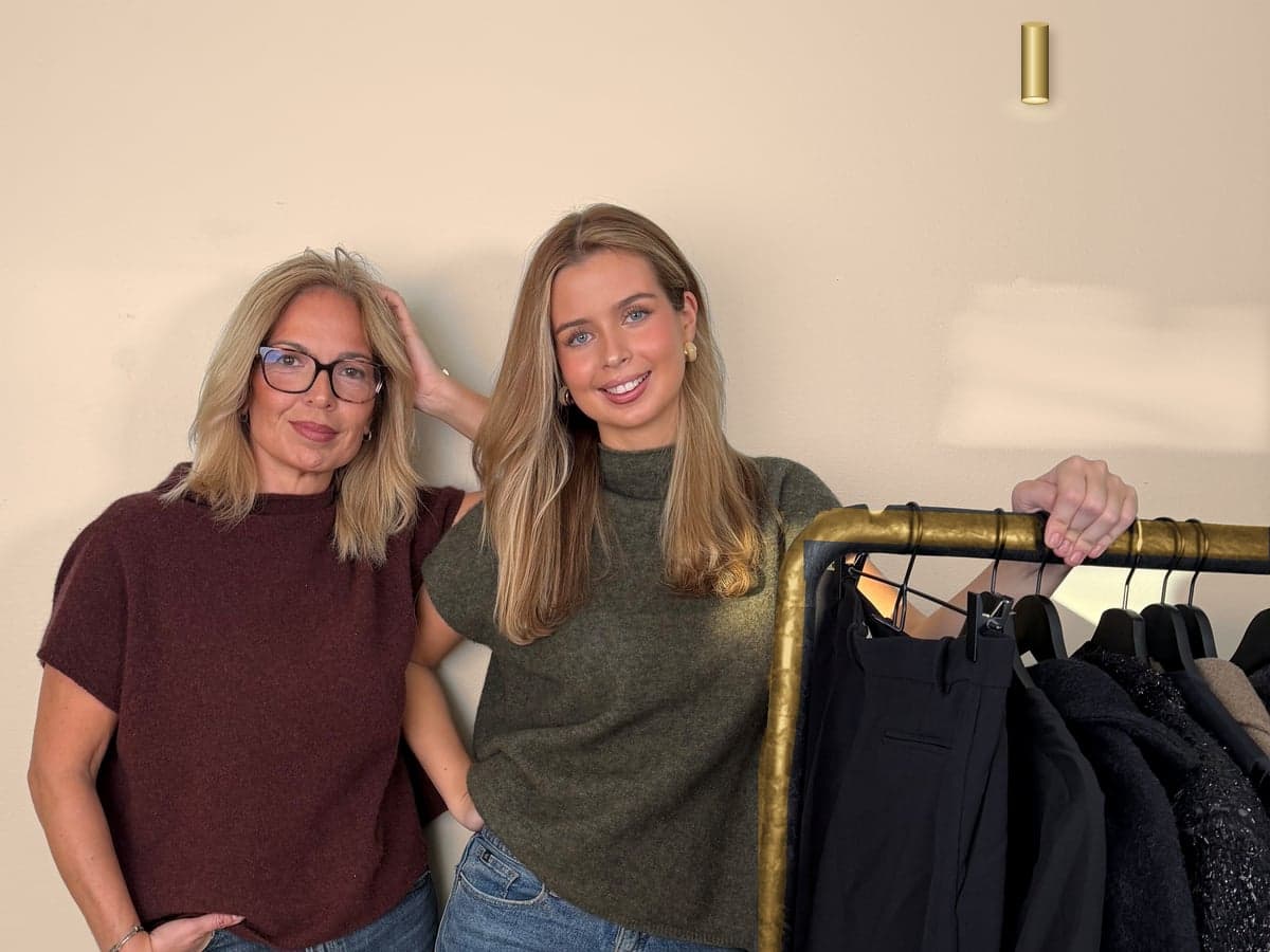 Manuela och Sophia, mor och dotter, vid en klädstång i mässing med svarta plagg
